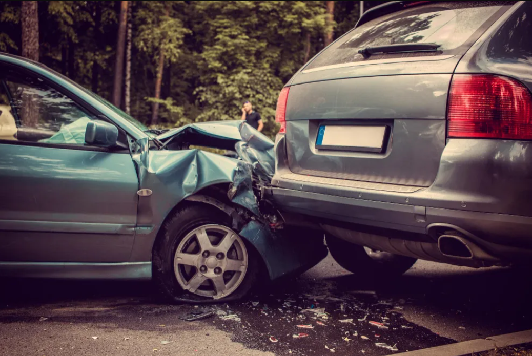 A silver sedan has collided with the rear of a gray SUV on a tree-lined road. Both vehicles show visible damage from the accident, highlighting scenarios often addressed within our Practice Areas.