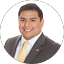 Man in a suit and yellow tie smiling, posing for a professional headshot against a white background.