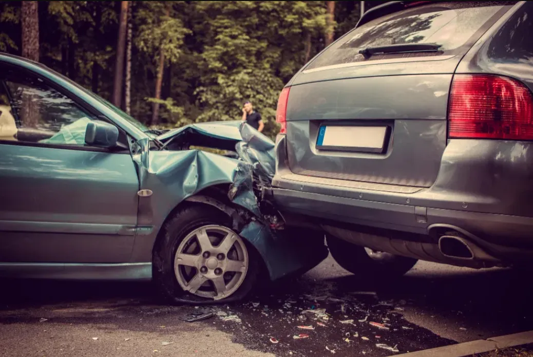 A silver sedan has collided with the rear of a gray SUV on a tree-lined road. Both vehicles show visible damage from the accident, highlighting scenarios often addressed within our Practice Areas.